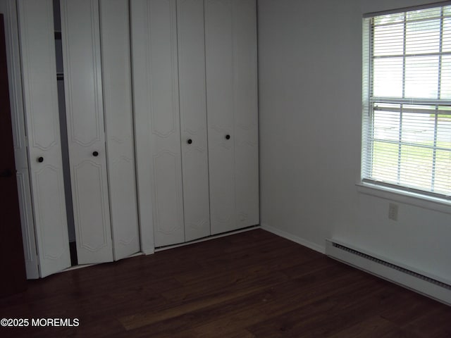 unfurnished bedroom with dark hardwood / wood-style flooring and a baseboard radiator