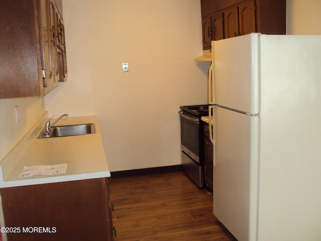 kitchen featuring white refrigerator, dark wood-type flooring, electric range, and sink