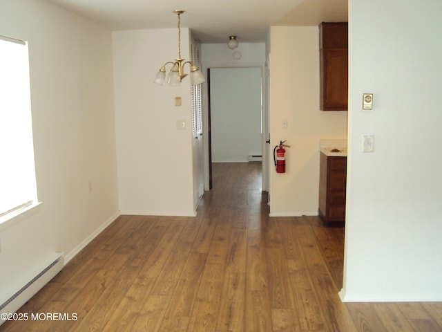 interior space featuring hardwood / wood-style flooring, an inviting chandelier, and a baseboard heating unit