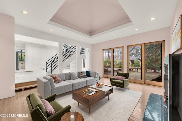 living room featuring a raised ceiling and light wood-type flooring