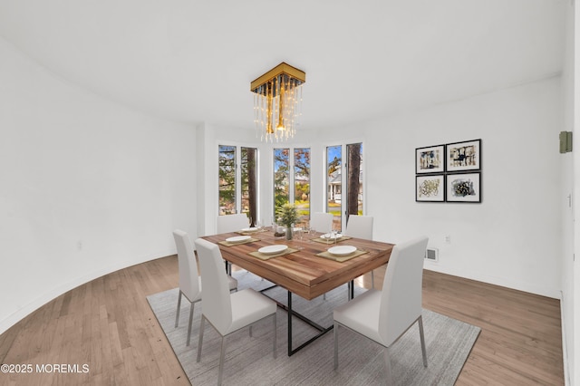 dining area with light hardwood / wood-style floors and a chandelier