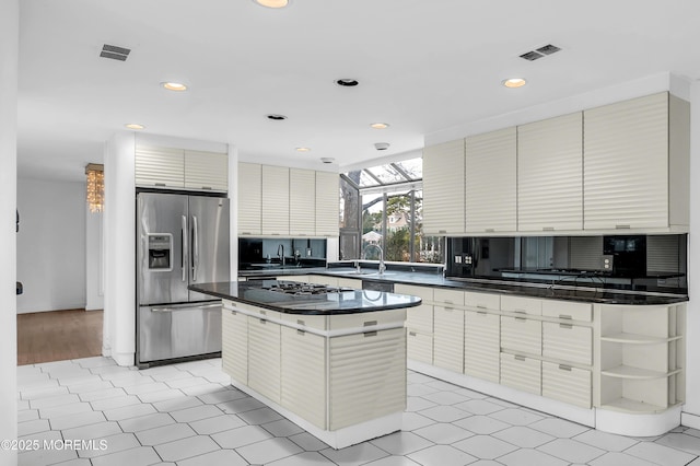 kitchen featuring stainless steel fridge, sink, a kitchen island, and gas cooktop