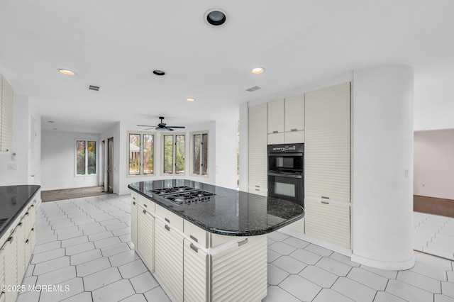 kitchen featuring ceiling fan, stainless steel gas cooktop, double oven, a breakfast bar area, and a kitchen island