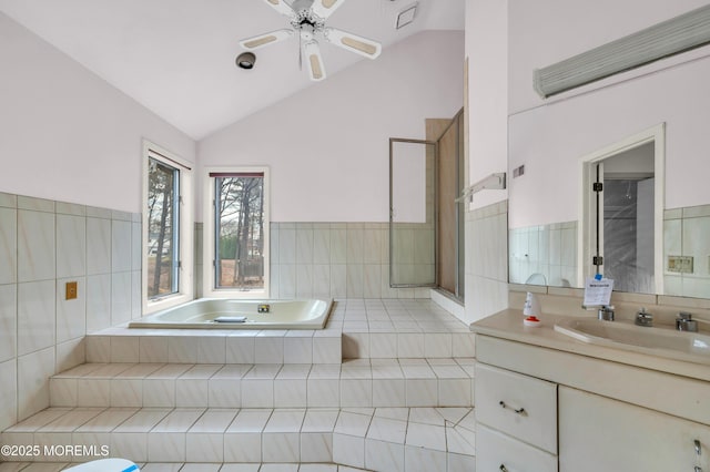 bathroom with tiled tub, vanity, and lofted ceiling