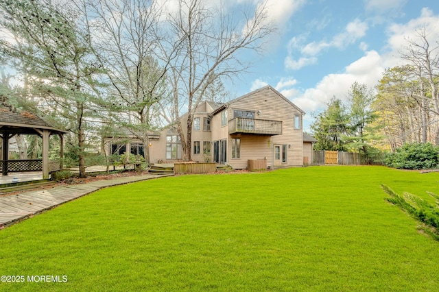 rear view of house with a gazebo, a balcony, a yard, and a wooden deck