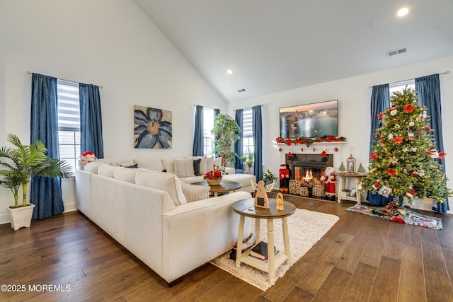 living room featuring a tile fireplace, dark hardwood / wood-style flooring, and high vaulted ceiling