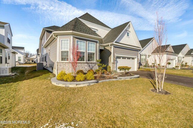 view of front of home with central AC unit, a front yard, and a garage