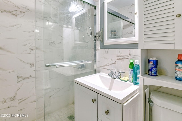 bathroom with tile walls, a shower with door, vanity, and toilet