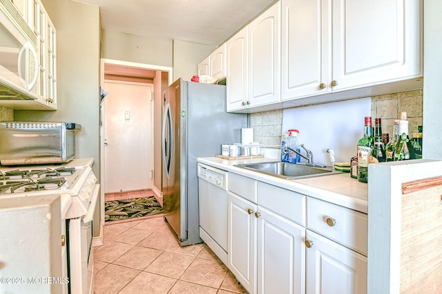 kitchen featuring white appliances, white cabinets, light tile patterned floors, sink, and tasteful backsplash