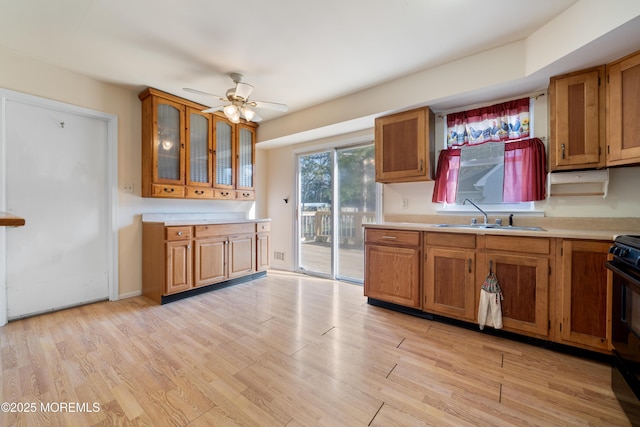 kitchen with sink, black stove, ceiling fan, and light hardwood / wood-style flooring