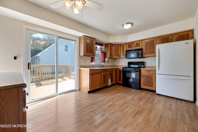 kitchen featuring sink, light hardwood / wood-style floors, ceiling fan, and black appliances