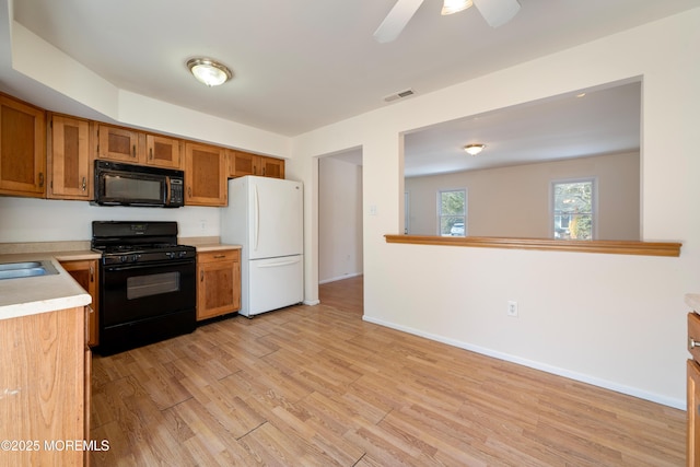 kitchen featuring sink, light hardwood / wood-style floors, ceiling fan, and black appliances