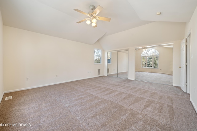 unfurnished bedroom featuring two closets, ceiling fan, light carpet, and lofted ceiling