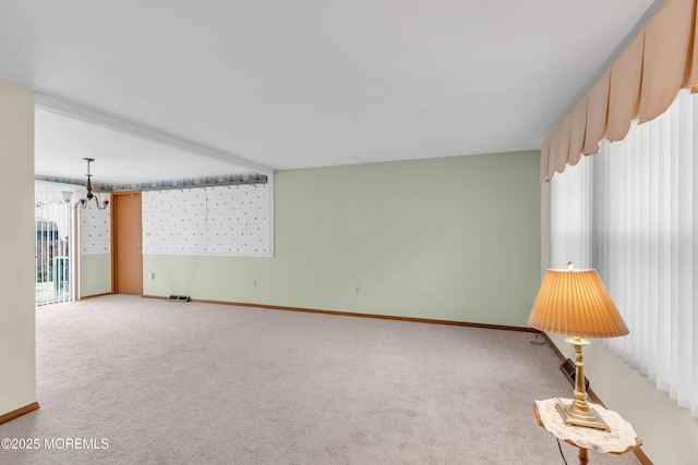 unfurnished room with carpet floors, a healthy amount of sunlight, and a notable chandelier