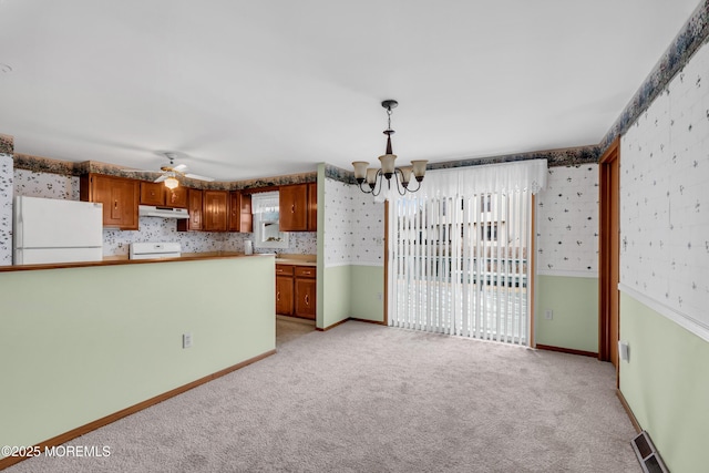 kitchen with light carpet, ceiling fan with notable chandelier, hanging light fixtures, white fridge, and range