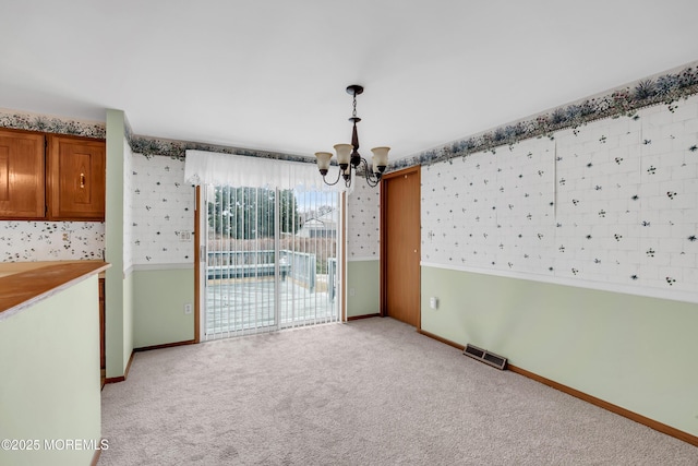 carpeted spare room featuring a chandelier