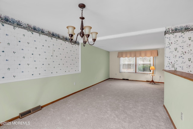 carpeted spare room with a chandelier