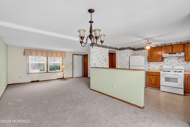 kitchen featuring decorative light fixtures, light colored carpet, white appliances, and ceiling fan with notable chandelier