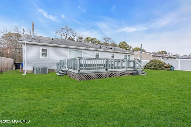 rear view of property featuring central air condition unit, a lawn, and a wooden deck