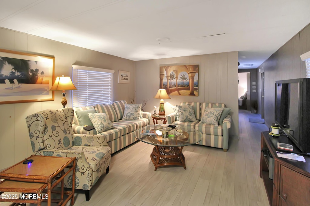 living room with light wood-type flooring and wooden walls