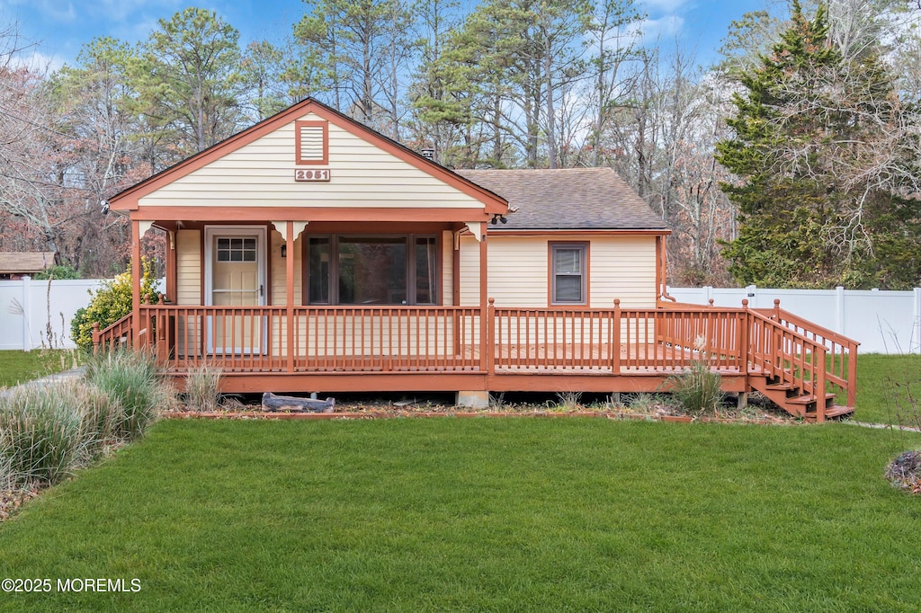 back of property with a lawn and a wooden deck