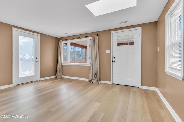 foyer with a skylight and light hardwood / wood-style flooring