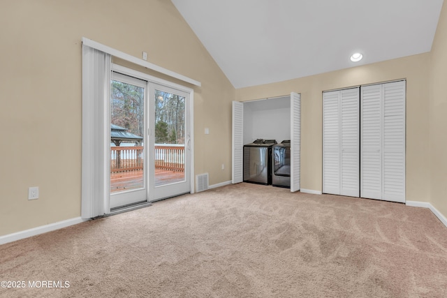 interior space featuring washer and dryer, light colored carpet, and vaulted ceiling