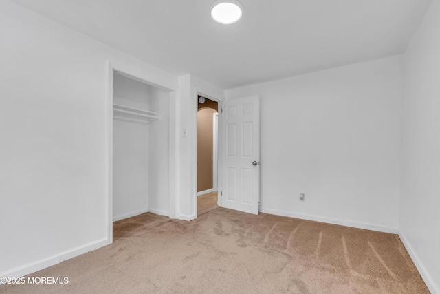 unfurnished bedroom featuring light carpet and a closet