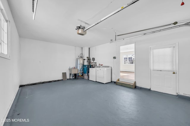 garage featuring washer and clothes dryer, sink, a garage door opener, and water heater