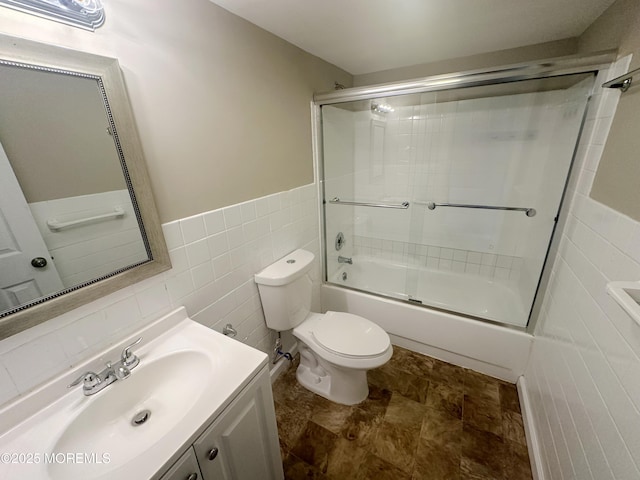 full bathroom featuring shower / bath combination with glass door, vanity, tile walls, and toilet