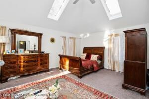 bedroom featuring carpet, lofted ceiling with skylight, and ceiling fan