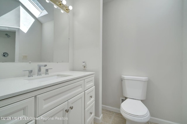 bathroom featuring tile patterned flooring, vanity, toilet, and a skylight