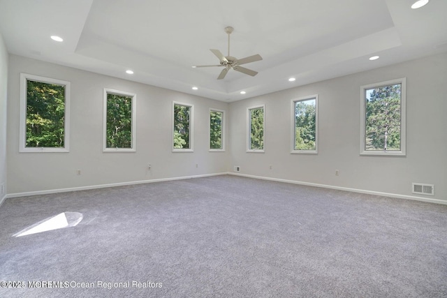 carpeted empty room with ceiling fan and a tray ceiling