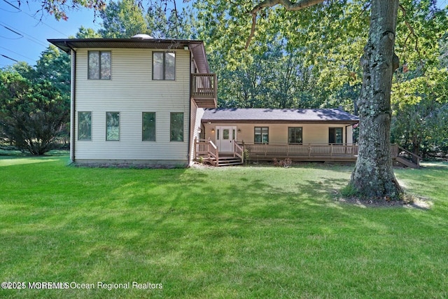 rear view of house with a balcony and a yard