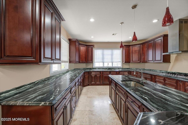 kitchen featuring pendant lighting, stainless steel gas stovetop, wall chimney range hood, and sink