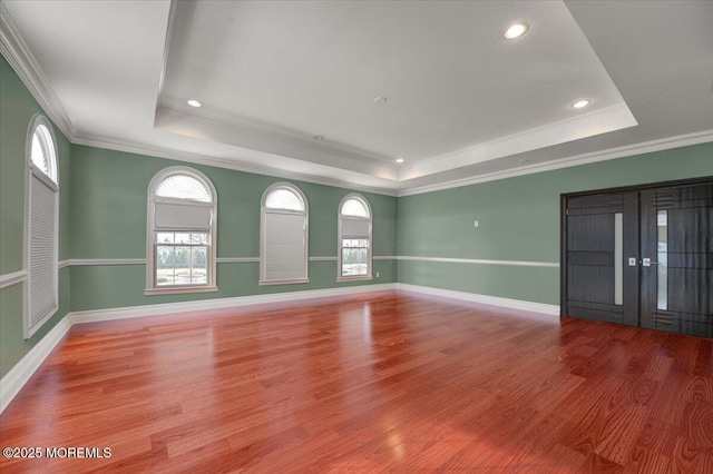 interior space featuring hardwood / wood-style flooring, ornamental molding, and a tray ceiling