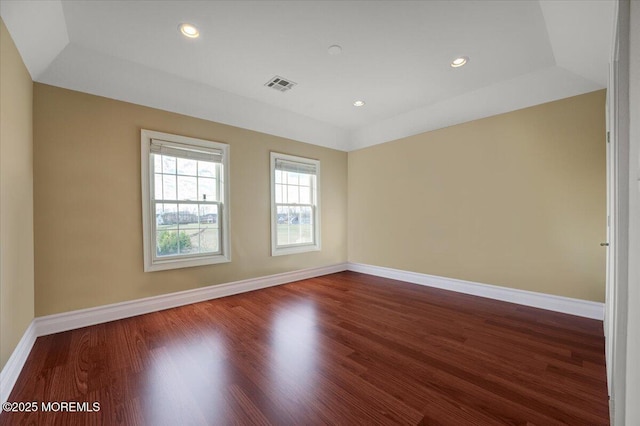 unfurnished room with dark hardwood / wood-style floors and a tray ceiling