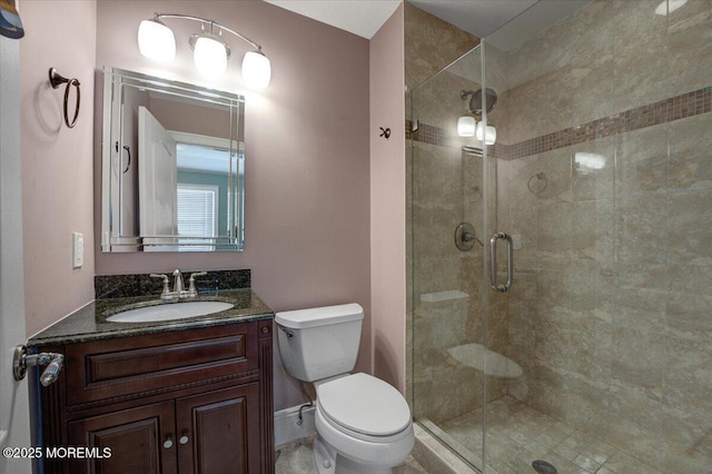 bathroom with vanity, toilet, and a shower with door