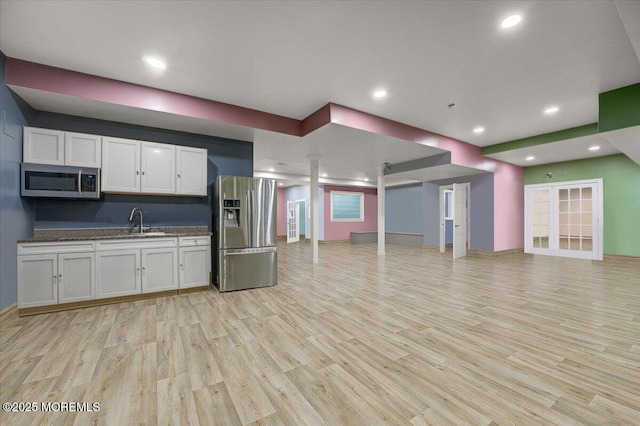 kitchen with sink, white cabinets, light hardwood / wood-style floors, and appliances with stainless steel finishes