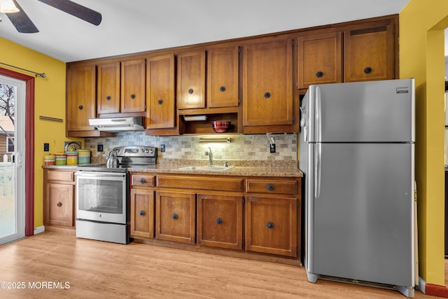 kitchen featuring decorative backsplash, light stone counters, stainless steel appliances, ceiling fan, and sink