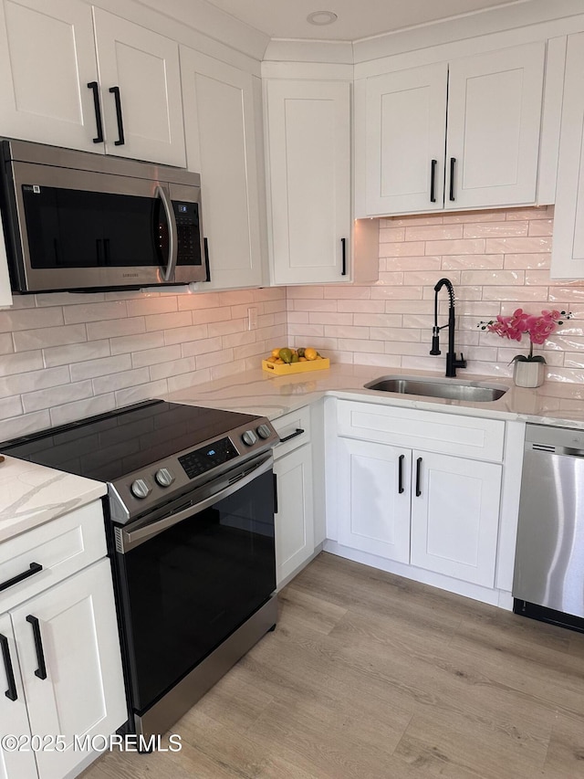 kitchen with decorative backsplash, appliances with stainless steel finishes, sink, and white cabinetry