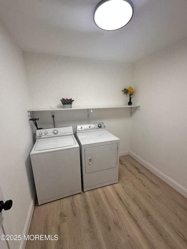 laundry room with separate washer and dryer and light hardwood / wood-style flooring