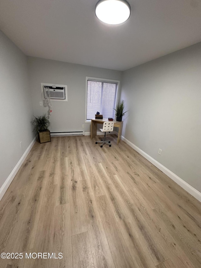 unfurnished office featuring light wood-type flooring, a baseboard radiator, and a wall unit AC