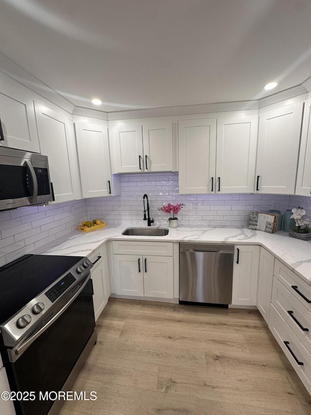 kitchen featuring sink, white cabinets, appliances with stainless steel finishes, and light hardwood / wood-style flooring