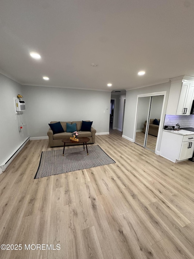 living room with baseboard heating, a wall unit AC, light hardwood / wood-style flooring, and crown molding