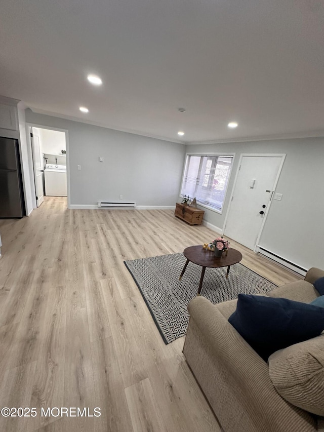 living room featuring a baseboard heating unit, light wood-type flooring, and washer / clothes dryer