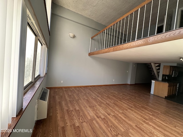 unfurnished living room featuring a wall mounted AC, hardwood / wood-style floors, and a textured ceiling