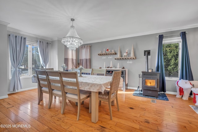 dining room featuring a wood stove, crown molding, a wealth of natural light, and light hardwood / wood-style flooring