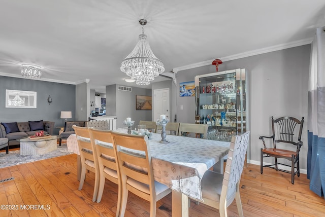 dining room featuring crown molding, a chandelier, and light hardwood / wood-style floors