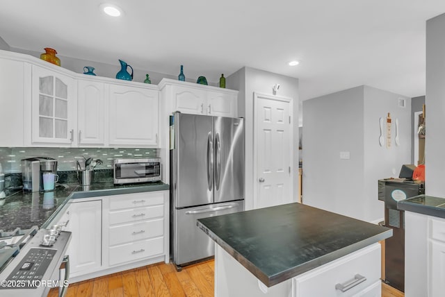 kitchen with decorative backsplash, light wood-type flooring, white cabinetry, and appliances with stainless steel finishes